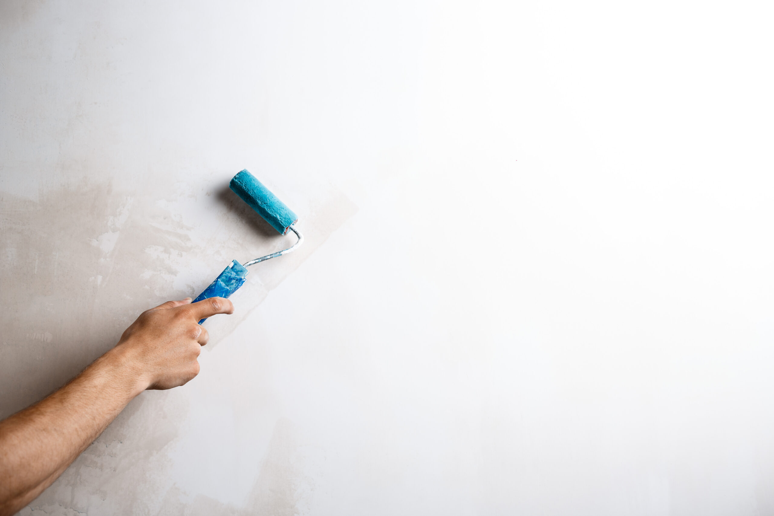 close up of hand painting wall with roller. copy space.